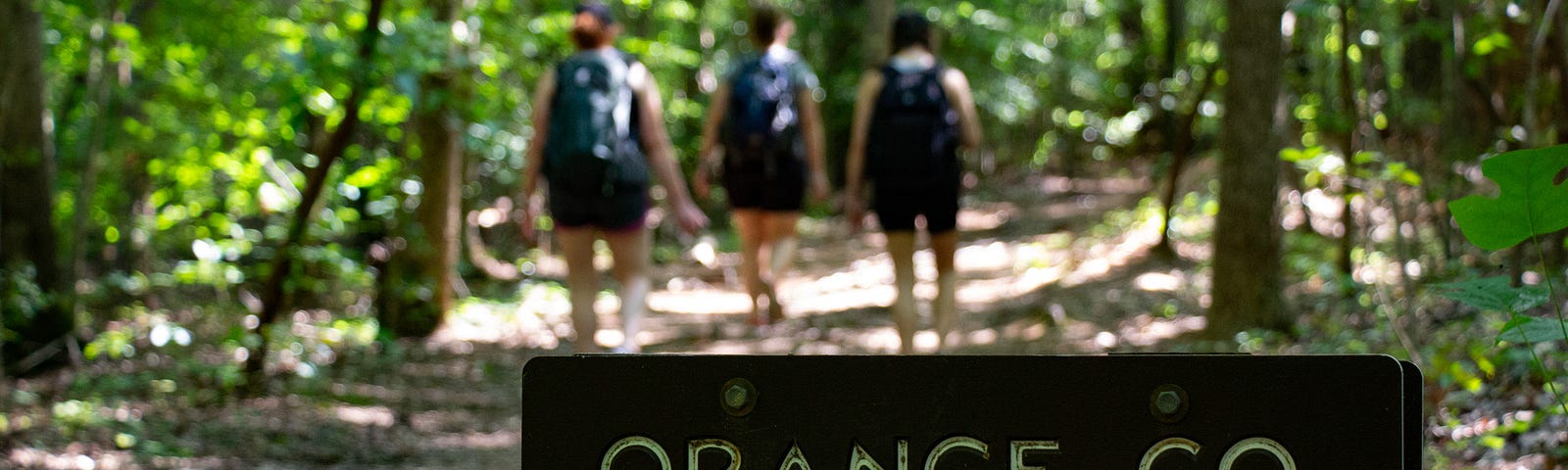 The NC State Park-sanctioned sign “Orange County” designating the line in the trail between Durham and Orange counties.