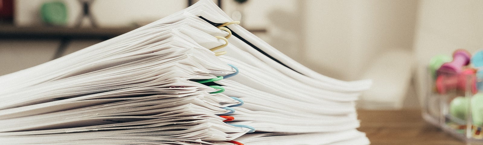 Reading glasses next to a stack of bound papers.