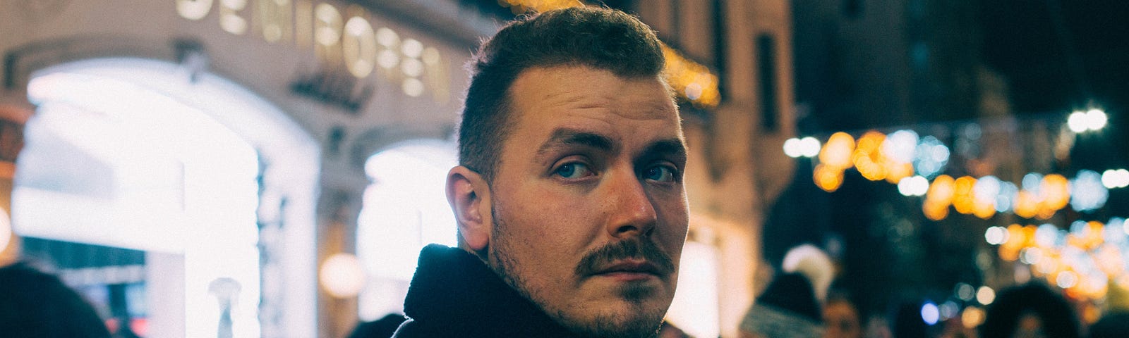 Man looking toward camera with nighttime street scene in background