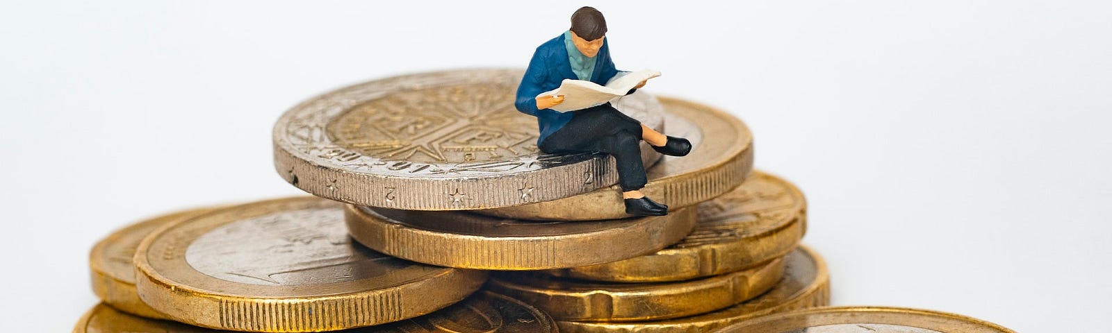 IMAGE: A little human figurine sitting atop a pile of euro coins, reading a newspaper