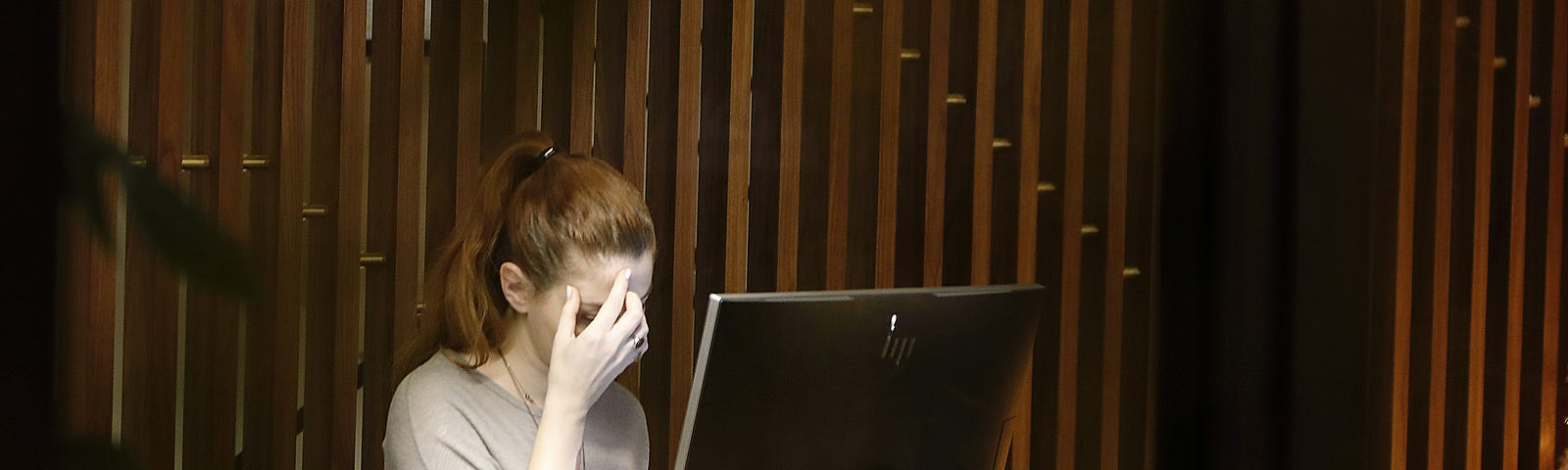 Woman rubbing her forehead in front of a computer