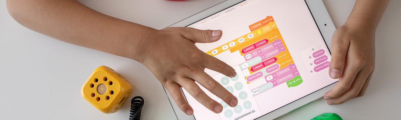 IMAGE: Two hands of a kid programming with intuitive tools (Scratch, from MIT) on a tablet