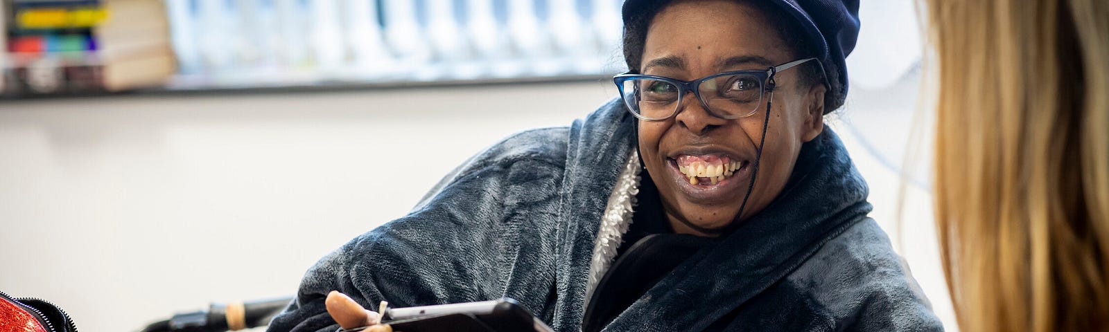 Black woman aged in her fifties smiling and holding a tablet
