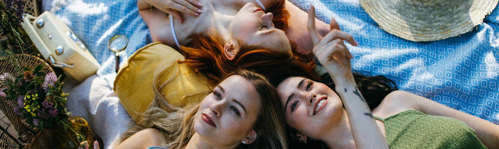 A photograph of three beautiful women, two of which are pointing at the sky