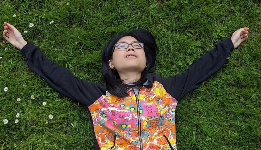 image of person lying down with arms open on grassfields