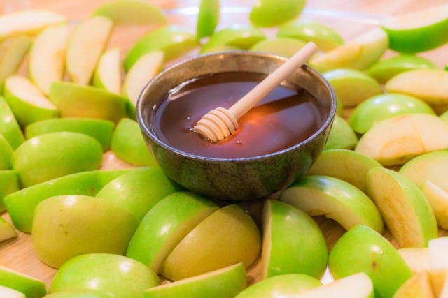 A plate of apples with a bowl of honey