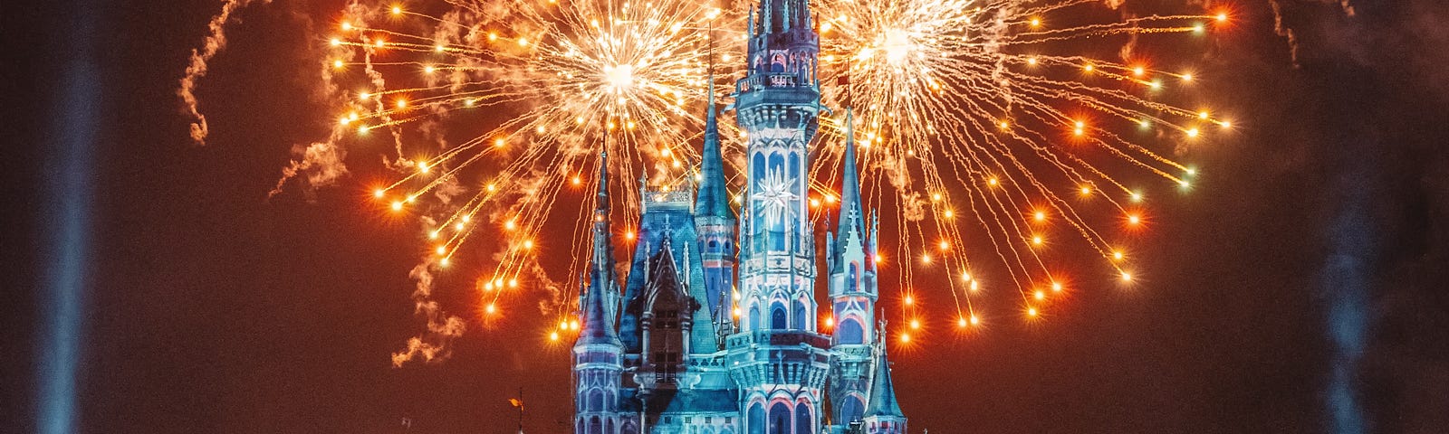 Disneyland in California, with fireworks erupting and glowing behind.