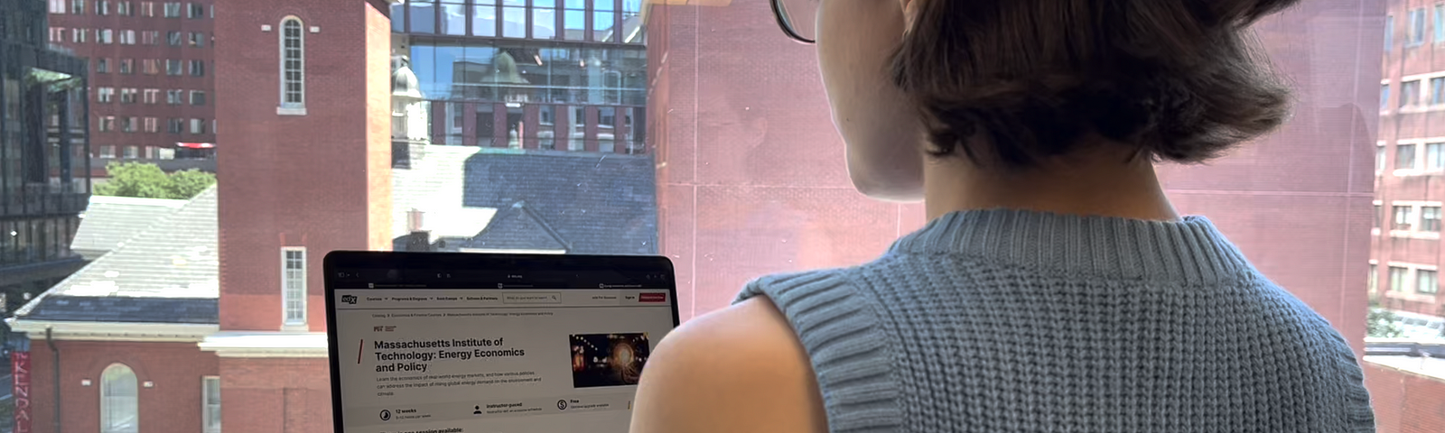 Photo of a learner with glasses looking at an MITx course on an open laptop.