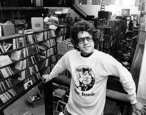 An image of Young Richard Foos in a record shop, wearing a sweater with the name of his former company “Rhino Records.”