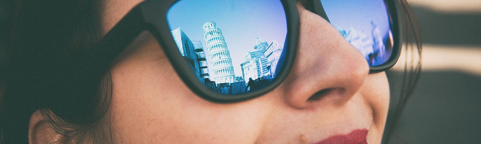 Close up of woman’s face with a beautiful view visible in her sunglasses