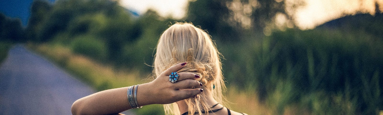 A blond girl looking at an open, empty road