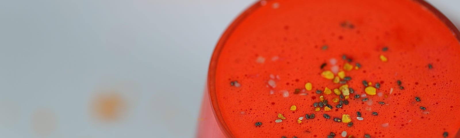 A glass of fresh juice topped with chia seeds and bee pollen.