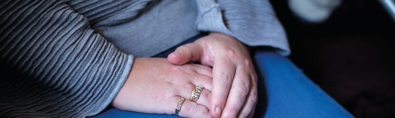 Hands crossed over on the lap of a victim-survivor of economic abuse