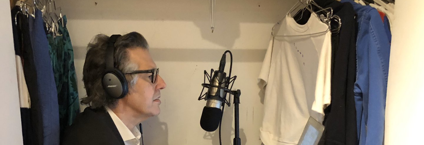 Photo of Ira Glass in a closet at home with his podcasting equipment