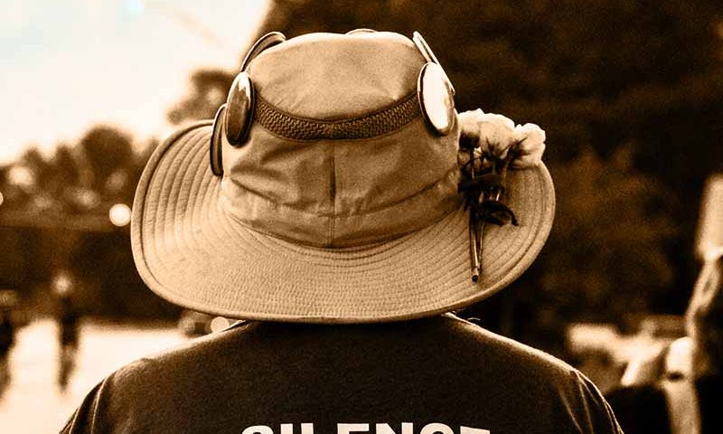 back of man wearing tee shirt stating silence is complicity