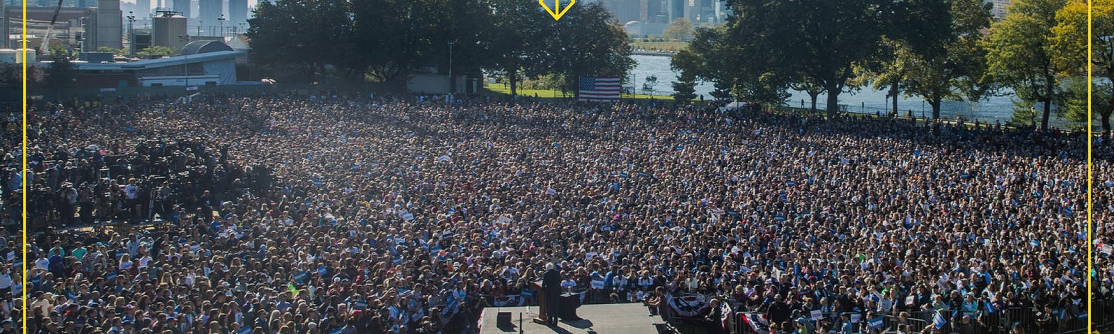 view from behind Sanders, addressing a large crowd of people