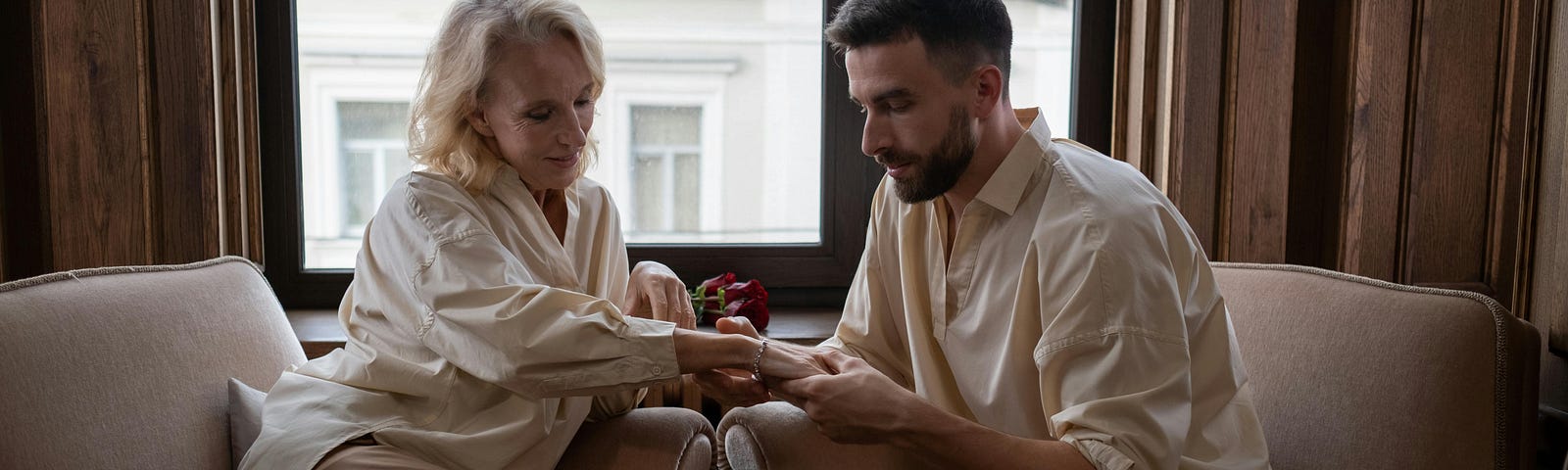 Young, dark-bearded man and blonde woman examining a gift bracelet on her wrist.