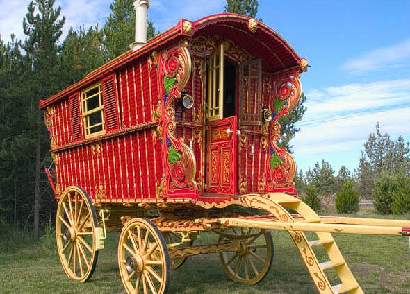 A red wooden vardo (gypsy wagon) with green and gold trim.