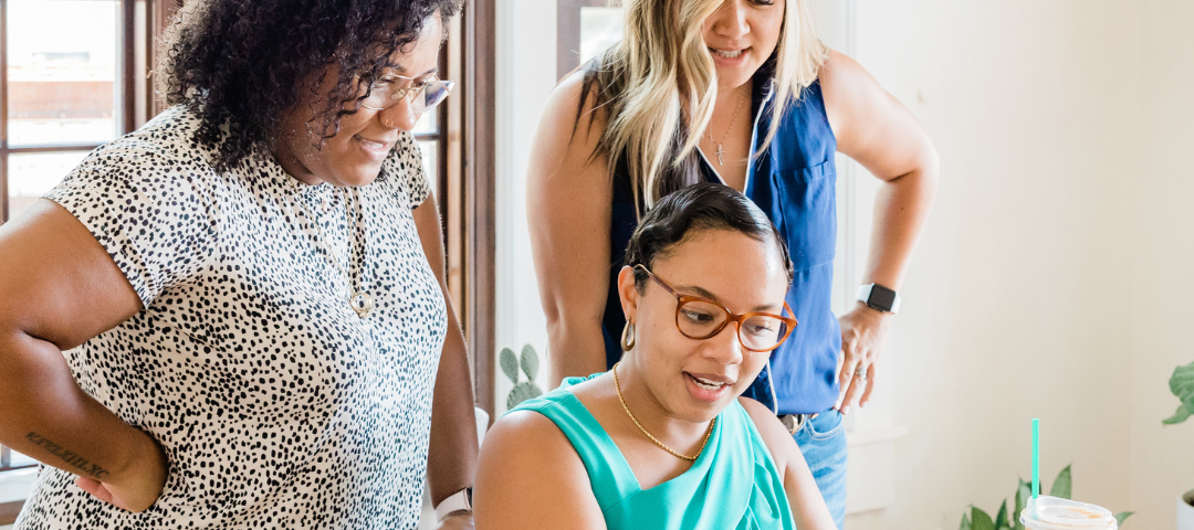 Three women talking about ethical digital marketing in front of a laptop