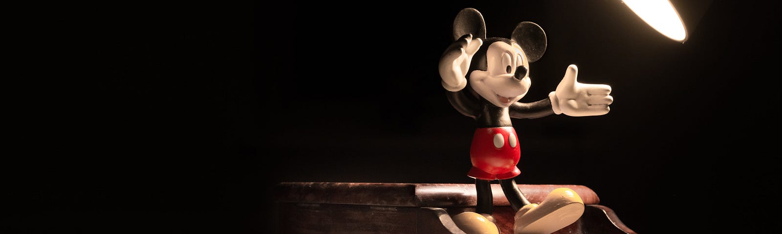 Mickey Mouse standing in the spotlight on a grand piano.