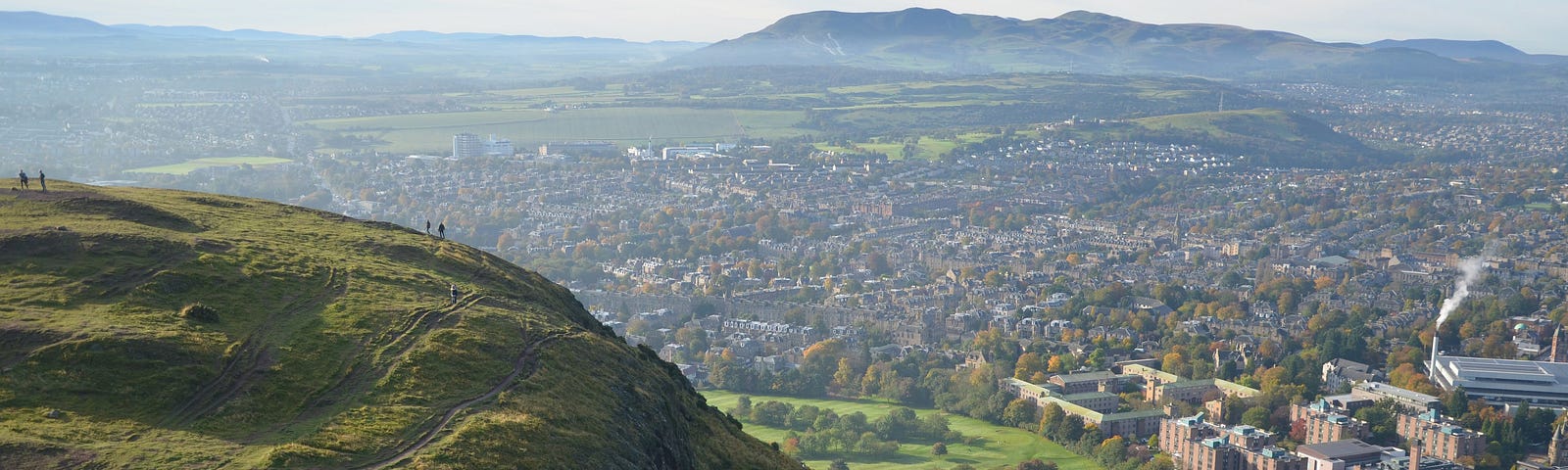 Standing atop a green hill, overlooking the city of Edinburgh.