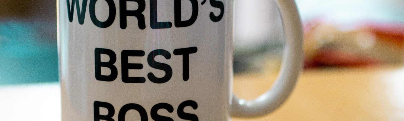 A mug that says “World’s Best Boss” is on a desk.