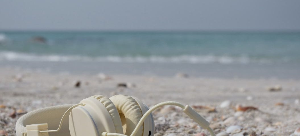 A close-up of a pair of white headphones on a beach