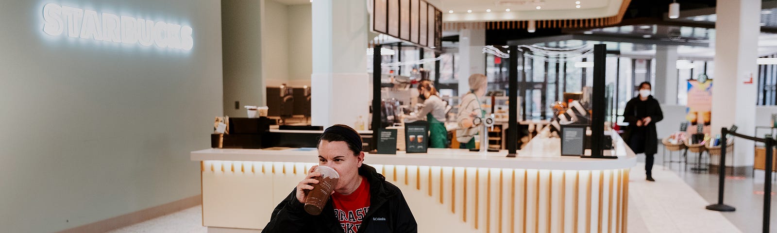 A person drinks coffee at the East Campus Starbucks