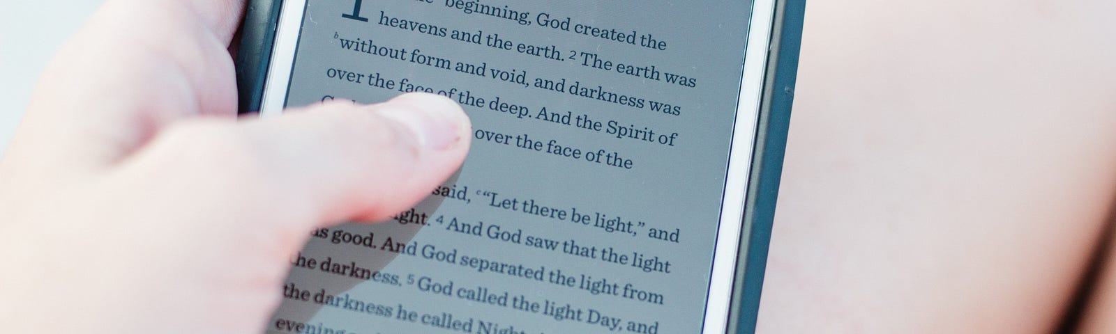 A cell phone with a digital version of the book of Genesis showing on the screen