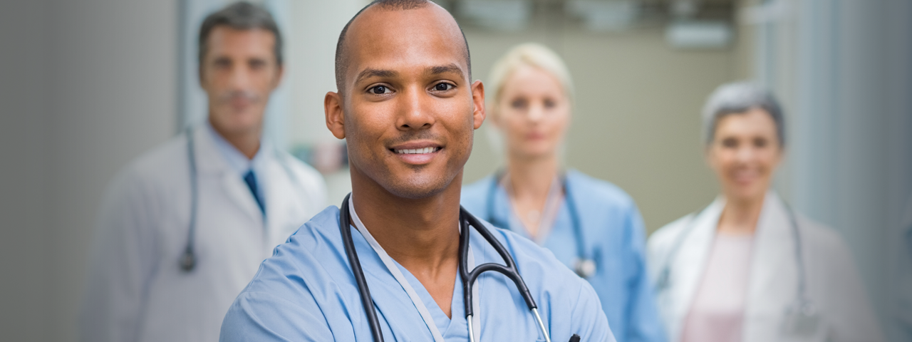 Confident male nurse in front of his medical team looking at the camera for the article to recognize Certified Nurses Day.