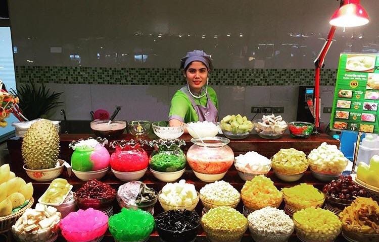 A smiling dessert seller lady stands behind her dessert stall in Bangkok, Thailand.
