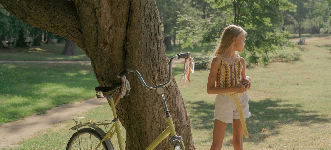 girl standing outside by a bike and tree