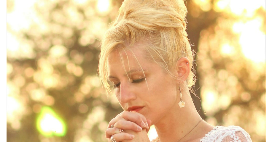 blonde woman with closed eyes praying