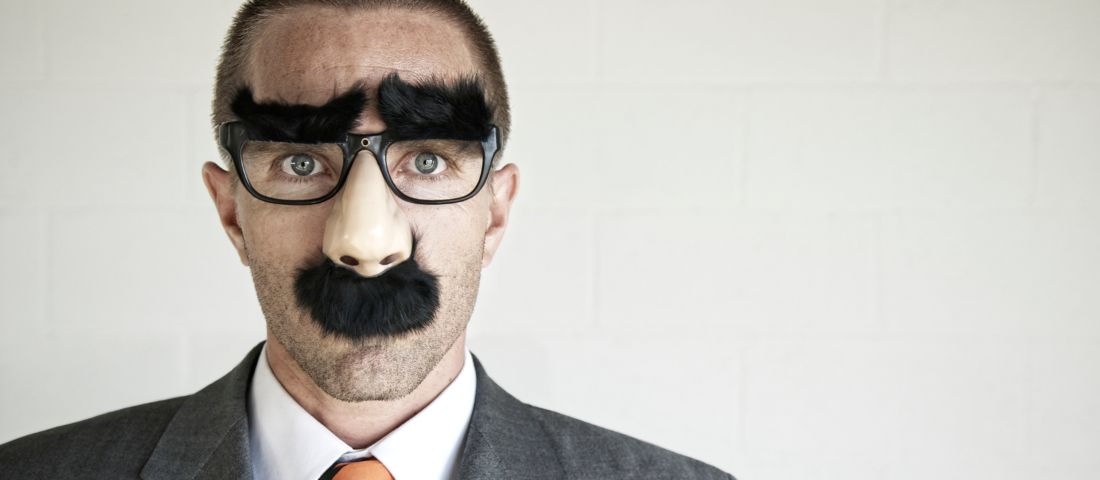A man wearing a suit in a nose and moustache glasses disguise
