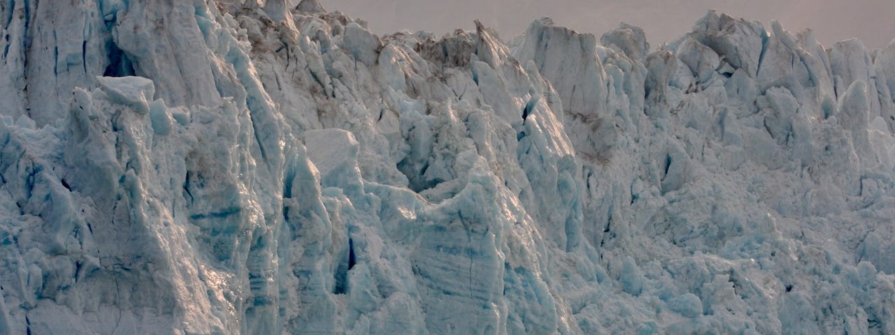 A wall of snow-covered rock lines an Alaskan cliff