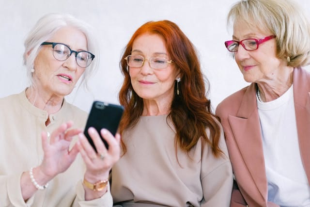 Three older women viewing social media on a smartphone.