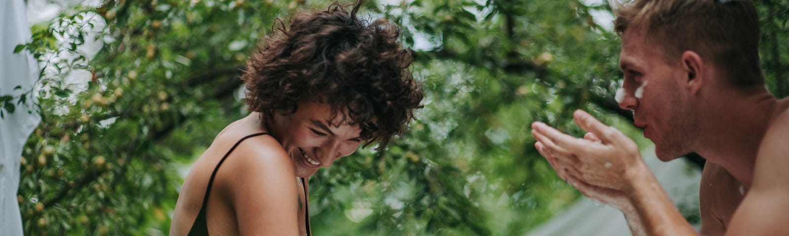 A couple playfully fights with one another outside in a green garden.