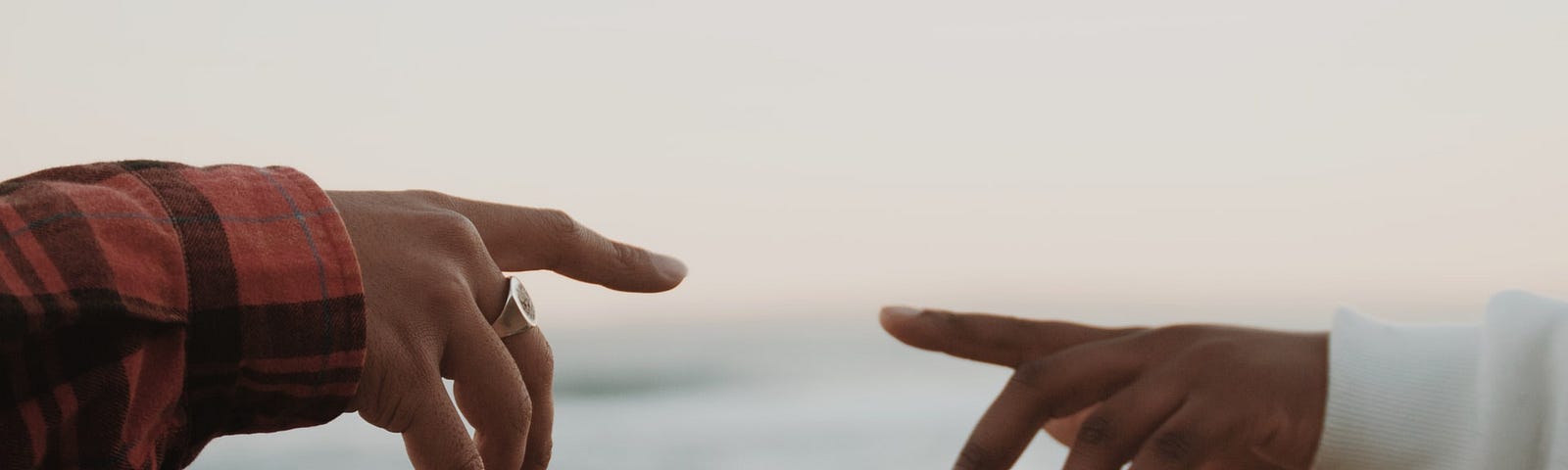 A woman’s hand is pointing to a man’s hand that is pointing back