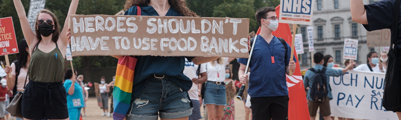 A woman at a protest holding a placard that says ‘Heroes shouldn’t have to use food banks’