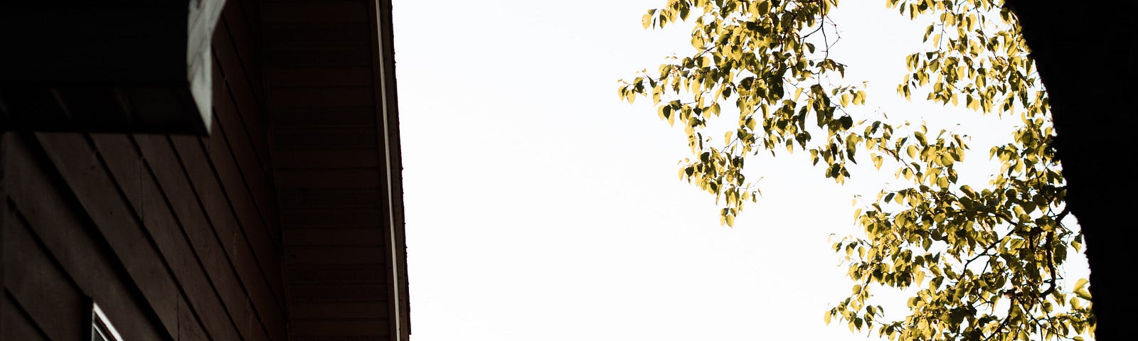 American Flag fluttering in the wind from it’s mast, angled off from a home’s corner.