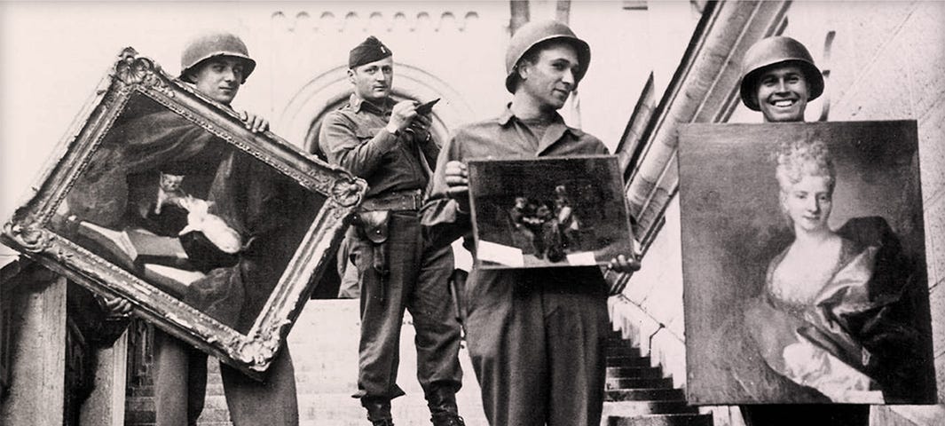 Four Monuments Men on the steps of a palace. Three are holding recovered artwork.
