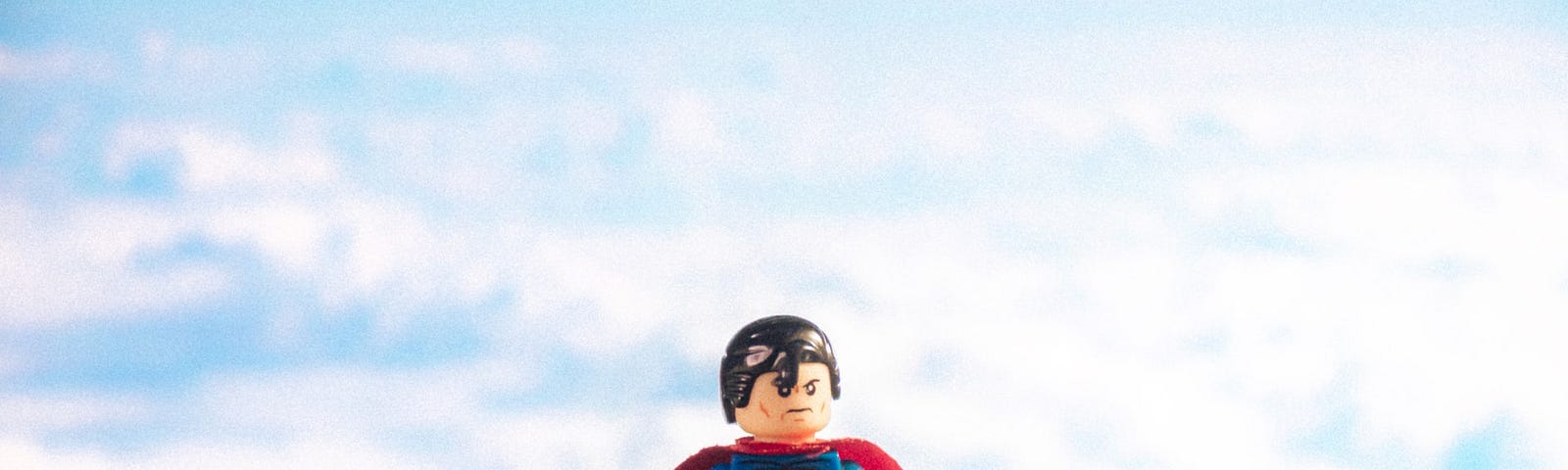 A lego Superman surrounded by white clouds, as if he’s hanging up there watching over the earth.