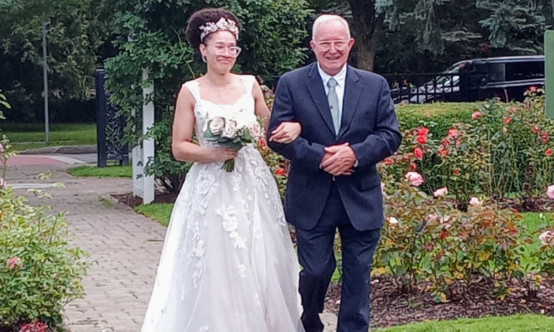 A photo of my father walking my daughter down the aisle in an August 2023 Schenectady NY park garden wedding