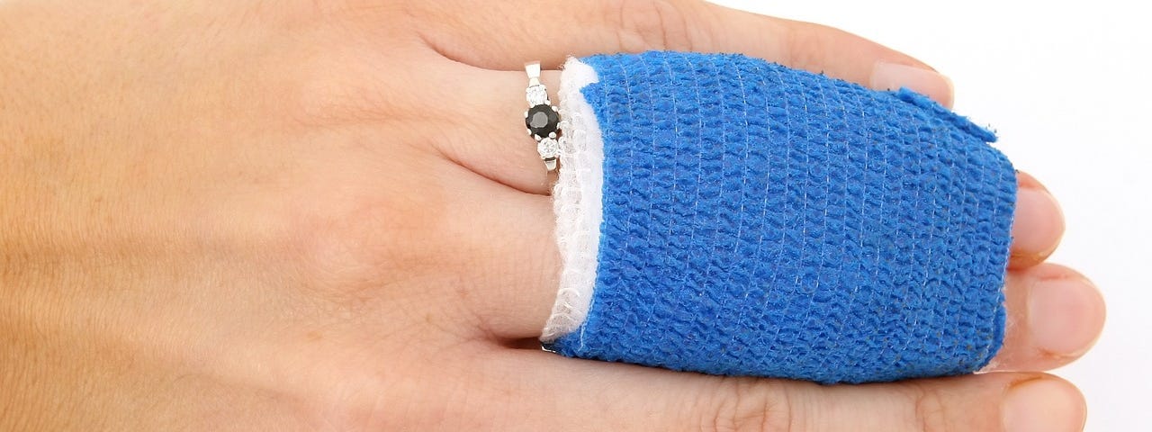 A women’s hand with two fingers wrapped in gauze to heal.