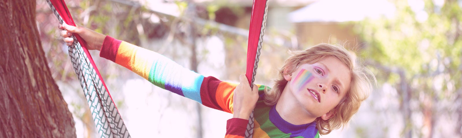 Photo of nonbinary child on swinging on a tree