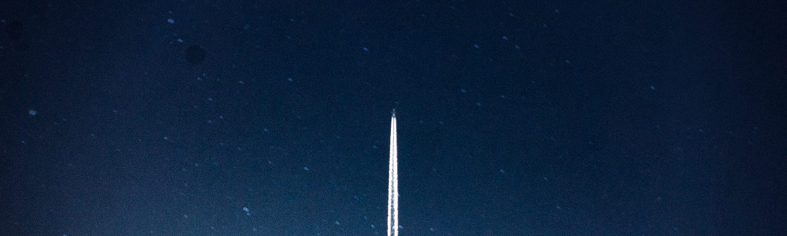 Photo of a distant airplane flying in a dusky sky