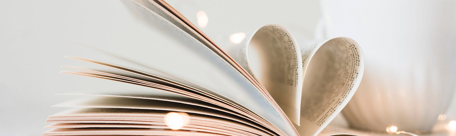 book with pages folded into a heart with white coffee cup sitting atop