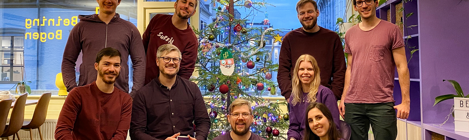 The Beining & Bogen team posing in front of a christmas tree at the office.