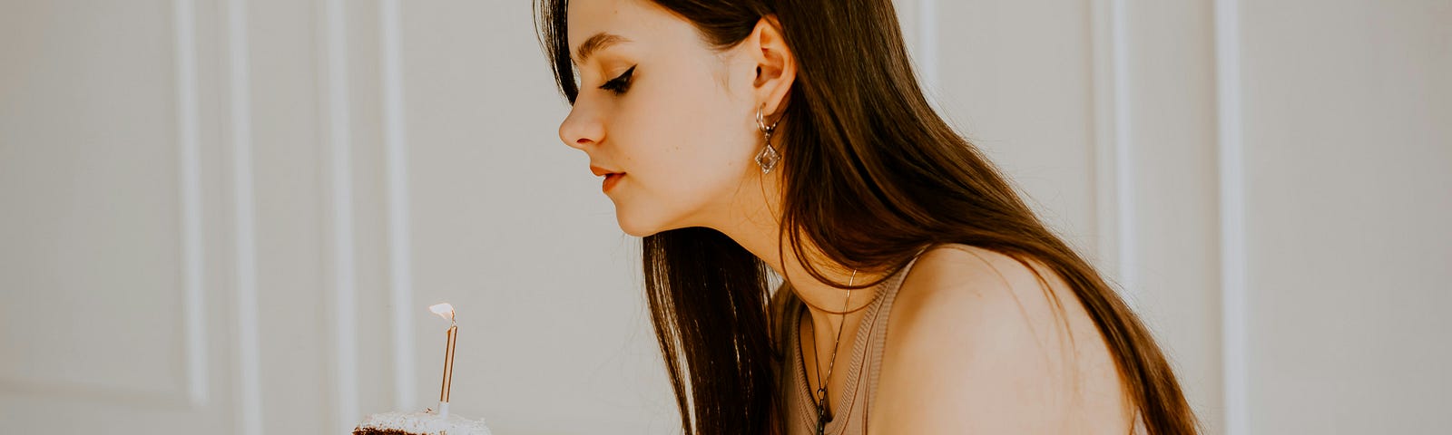 Young woman with a slice of cake with one candle