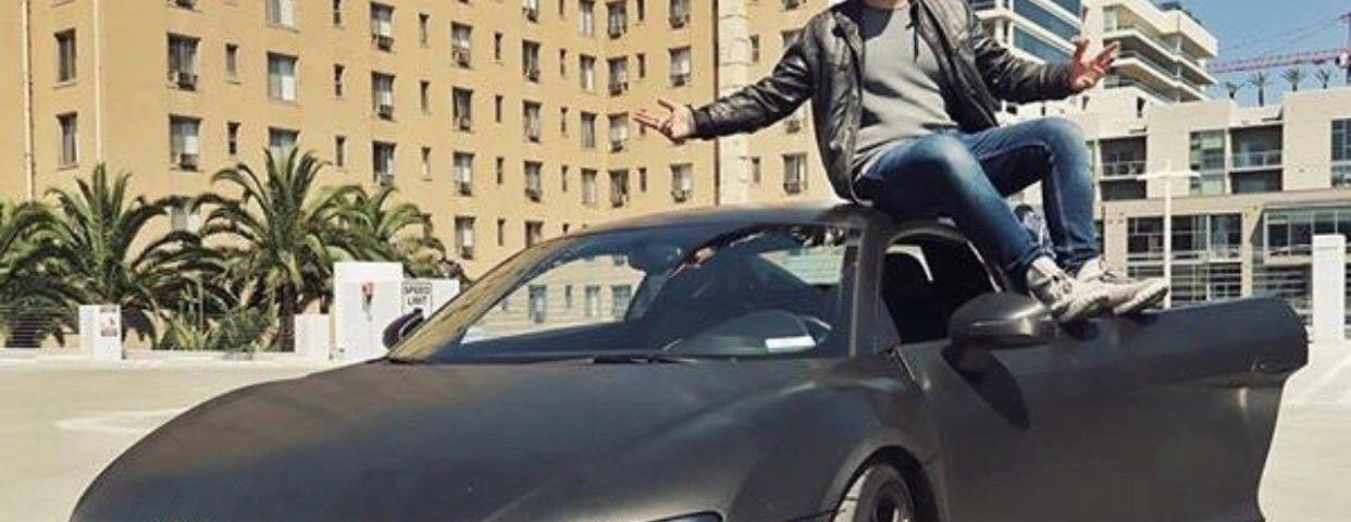 Erik Finman sitting on the hood of his car